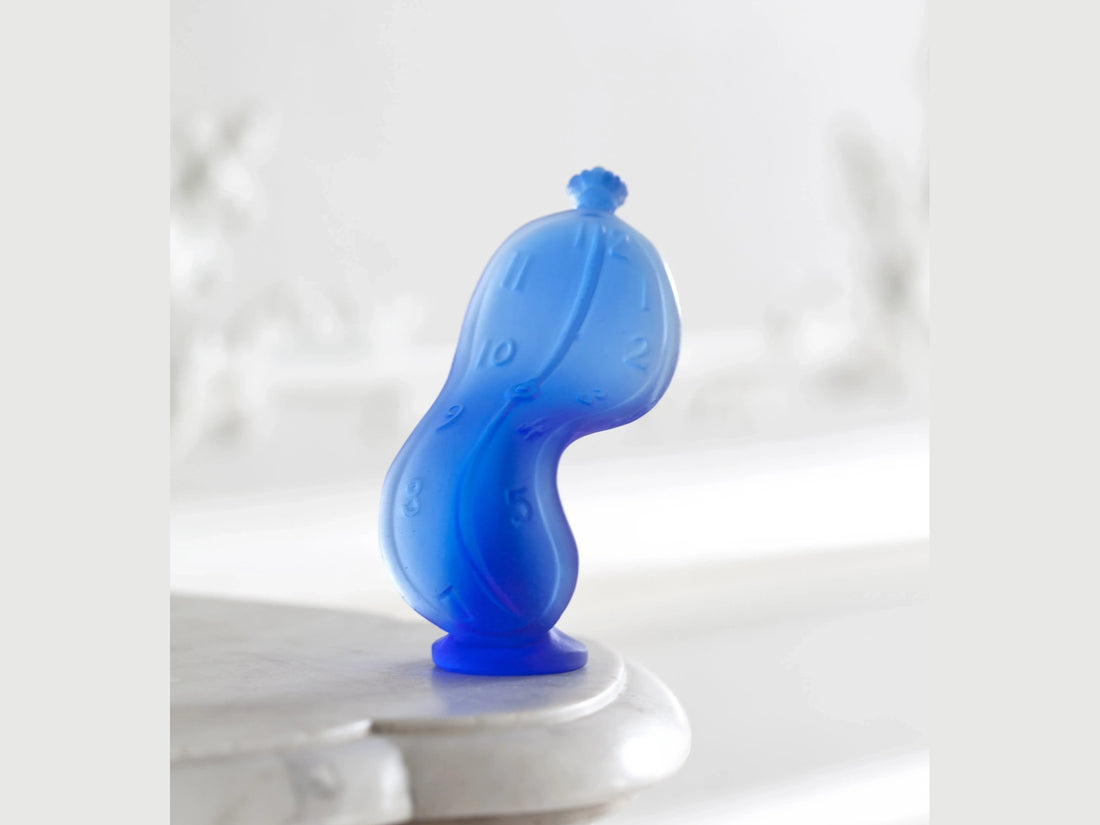 Daum Dance of Time by Salvador Dalí blue glass sculpture on a green background
