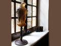 Daum amber-rose glass falcon sculpture on a dark pedestal by a window.