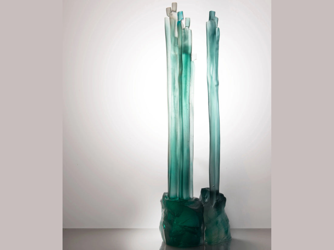 Daum Laurence Bonnel set featuring teal glass sculpted elements on a green background.