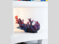 Daum Mer de Corail glass sculpture in blue and red displayed on a white shelf