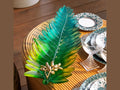 Daum Palm Beach large green leaf glass bowl with gold accents on a wooden table.