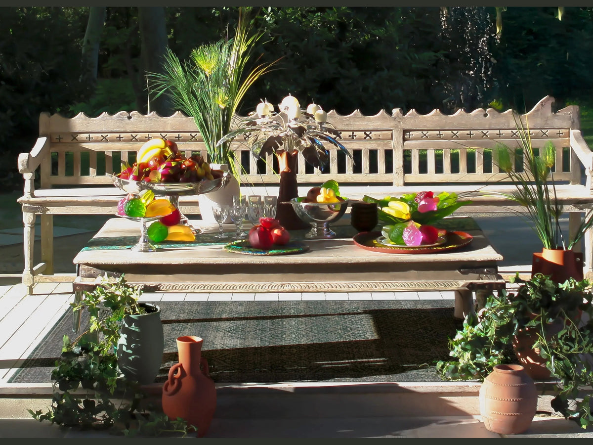 Daum Tutti Frutti Coupe filled with colorful fruit on a wooden outdoor table.