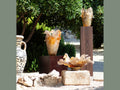 Three Daum Cavalcade centerpieces in iced brown glass displayed outdoors on plinths.