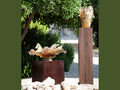 Daum Cavalcade Centerpiece in iced brown glass displayed on wooden pedestals outdoors