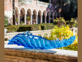 Daum Mer de Corail blue glass centerpiece on a stone ledge in a garden setting