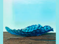 Daum Mer de Corail blue glass center piece on a rustic wooden surface