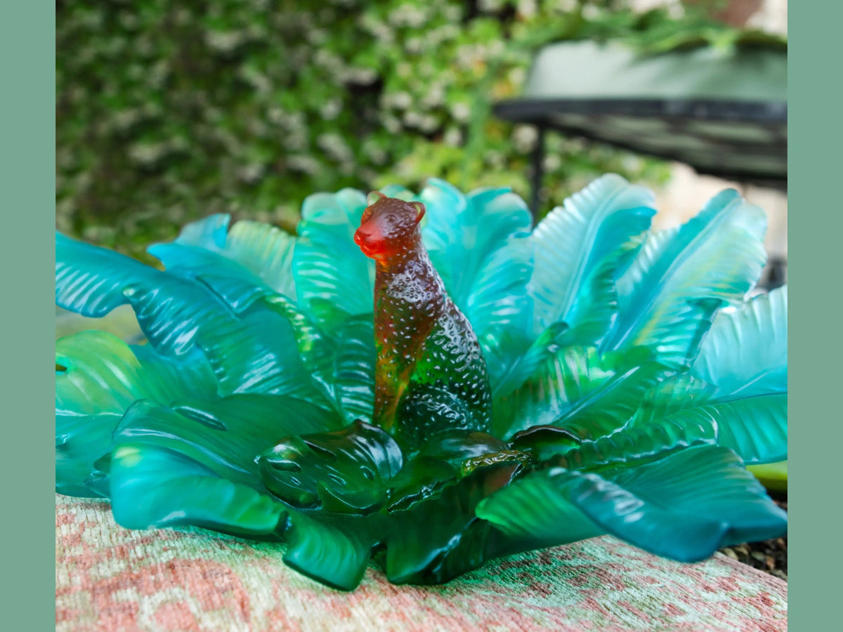 Daum Voyage Tropical glass centerpiece featuring a colorful tropical bird figurine.