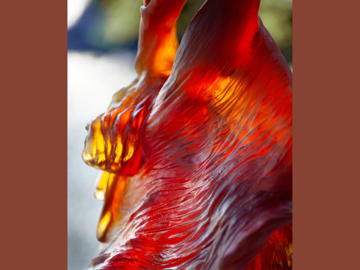 Close-up of a red and amber Daum glass sculpture with flowing, textured waves.
