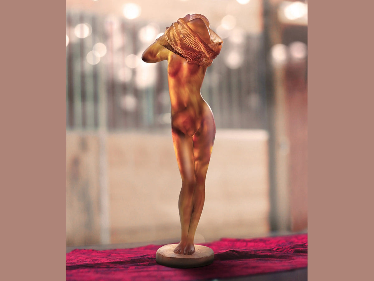 Daum Woman in a Sweater crystal sculpture by Nadine Enakieff on a red velvet surface.