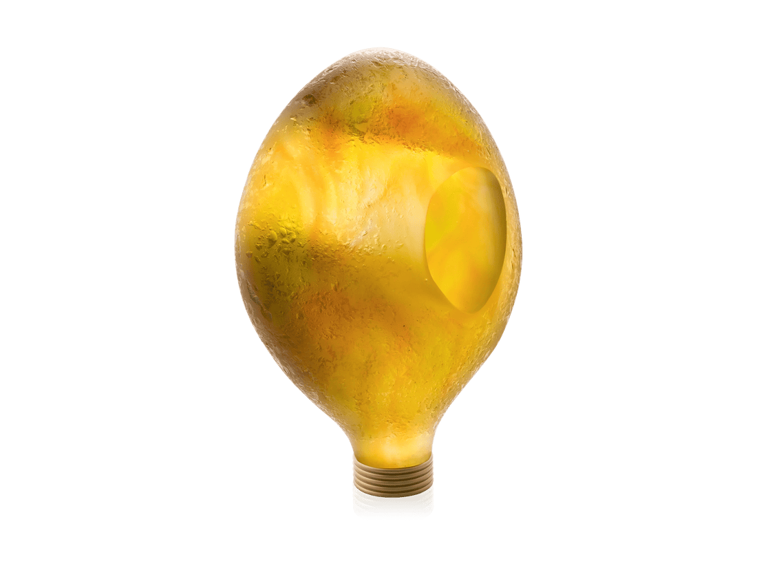 Daum Yeelen solaire sculpture in yellow glass shaped like a light bulb against a green background